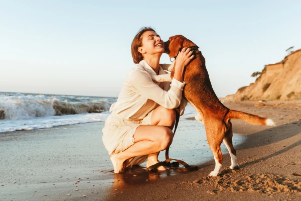 mujer acariciando a su perro en una playa